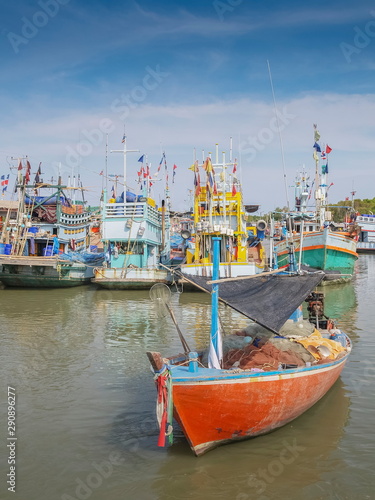 view of a small fishing boat floating in the sea around with many fishing ships and blue sky background, Puek Tian Fisherman Village, Phetchaburi, Thailand. photo
