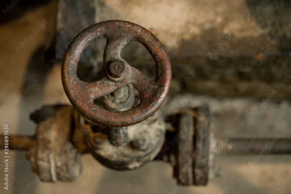 An aged rusty circle shaped tap in old abandoned factory. Close up of a metal faucet that has not been used for ages. An aged rusty circle shaped tap in old abandoned factory. Close up of a metal faucet that has not been used for ages.