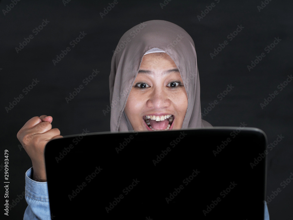 Muslim Lady Using Laptop Shows Winning Gesture, Receiving Good News on Her Email Muslim Lady Using Laptop Shows Winning Gesture, Receiving Good News on Her Email