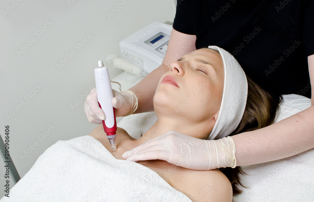 Beautiful woman lying and receiving ultrasonic exfoliation procedure of ultrasonic cleaning of part of body in beauty salon