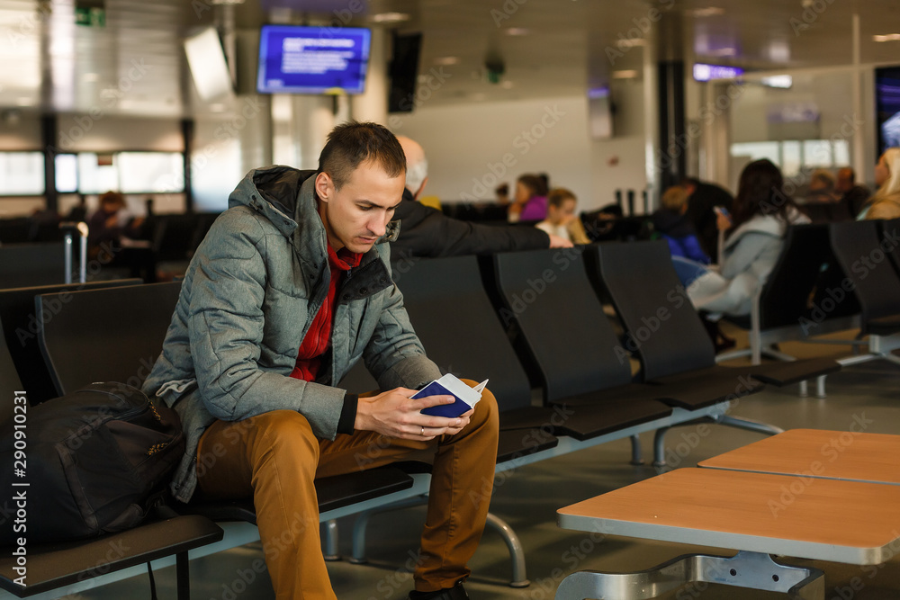 Mature businessman using mobile phone at the airport in the waiting room. Business man typing on smartphone in lounge area. Portrait of latin man sitting and holding passport with luggage. Mature businessman using mobile phone at the airport in the waiting room. Business man typing on smartphone in lounge area. Portrait of latin man sitting and holding passport with luggage.