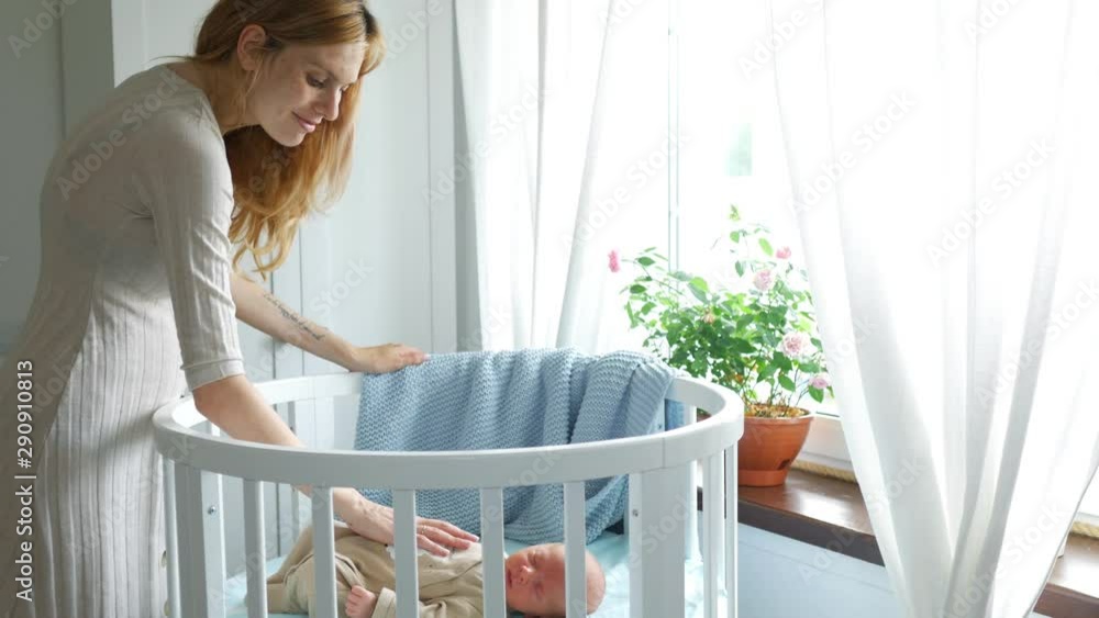 beautiful woman stroking a sleeping newborn baby in the crib beautiful woman stroking a sleeping newborn baby in the crib
