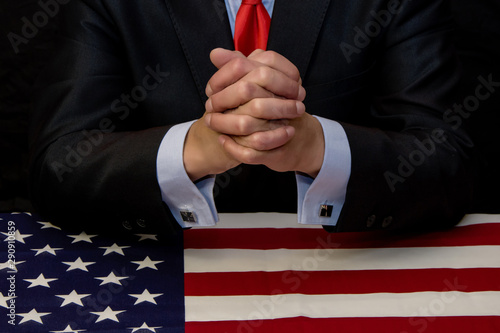 The politician-businessman clasped his fingers in a lock, sitting at the table covered with the American flag, the firmness of decisions responsible for the country