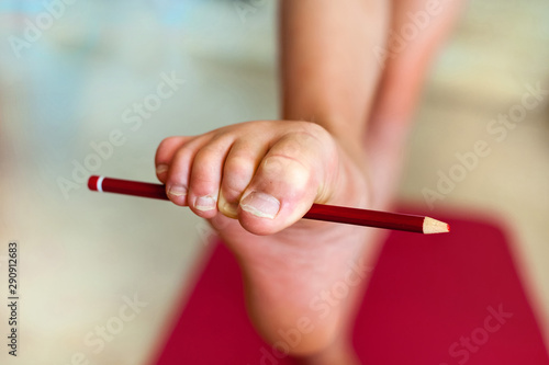 Girl doing exercises with a pencil for toes. Close-up