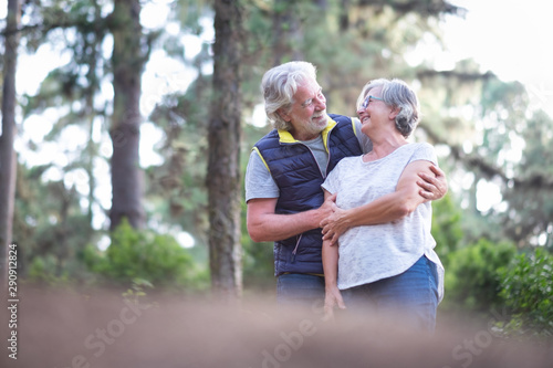 Happy senior couple with white hairs and large smiles in the woods. Casual clothing for excursion. Enjoying and protect the nature