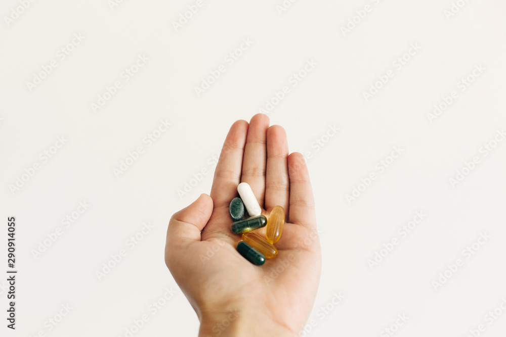 Hand holding omega 3, spirulina, chlorophyll,magnesium capsules on white wall background. Morning dose vitamin pills. Dietary supplements. Health support. Biologically active additives Hand holding omega 3, spirulina, chlorophyll,magnesium capsules on white wall background. Morning dose vitamin pills. Dietary supplements. Health support. Biologically active additives