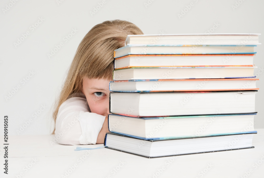 Beautiful little girl hiding behind a stack of books Beautiful little girl hiding behind a stack of books