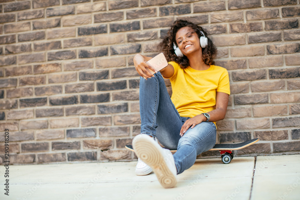 Beautiful afro girl taking selfie while sitting on skateboard Beautiful afro girl taking selfie while sitting on skateboard