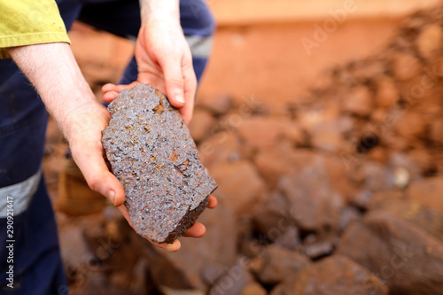 Close up picture of scientist geologist hands inspecting exploration on iron ore rock on open field mine site, Perth, Australia 