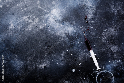 Syringe with blood on old concrete background. Top view.