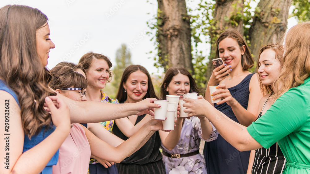 Group of girlfriends toasting with champagne in paper glass. Young people celebrating with champagne at party outdoors. Concept of hen-party Group of girlfriends toasting with champagne in paper glass. Young people celebrating with champagne at party outdoors. Concept of hen-party