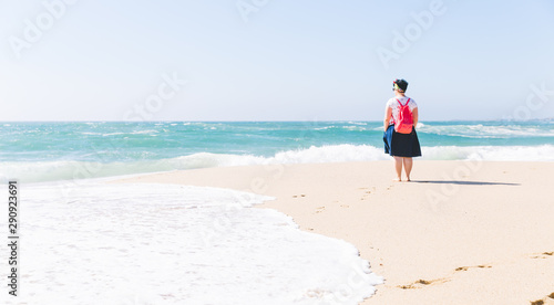 Lady with the pink bag standing in the beach ant watching o the Atlantic ocean, Portugal.