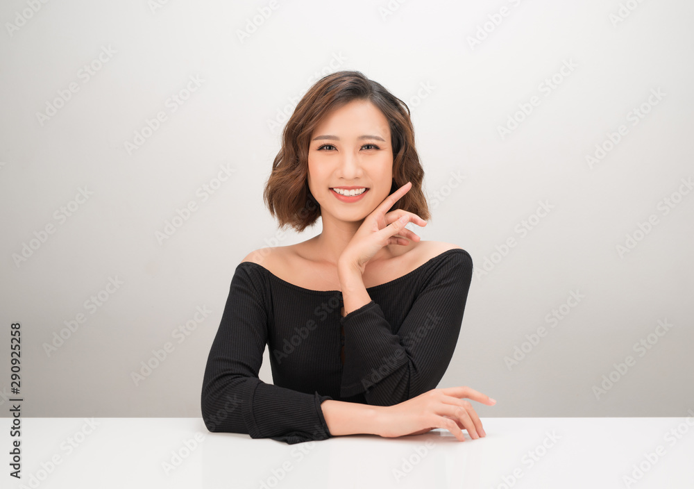 Pretty, happy, young asian woman in casual clothes sitting at the desk, isolated on white Pretty, happy, young asian woman in casual clothes sitting at the desk, isolated on white