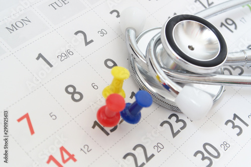 Regular medical examination concept, black stethoscope and push pins on calendar background