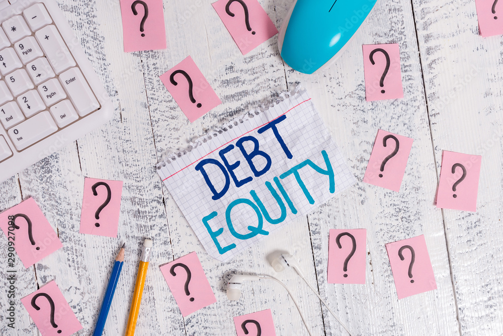 Writing note showing Debt Equity. Business concept for dividing companys total liabilities by its stockholders Writing tools and scribbled paper on top of the wooden table Writing note showing Debt Equity. Business concept for dividing companys total liabilities by its stockholders Writing tools and scribbled paper on top of the wooden table