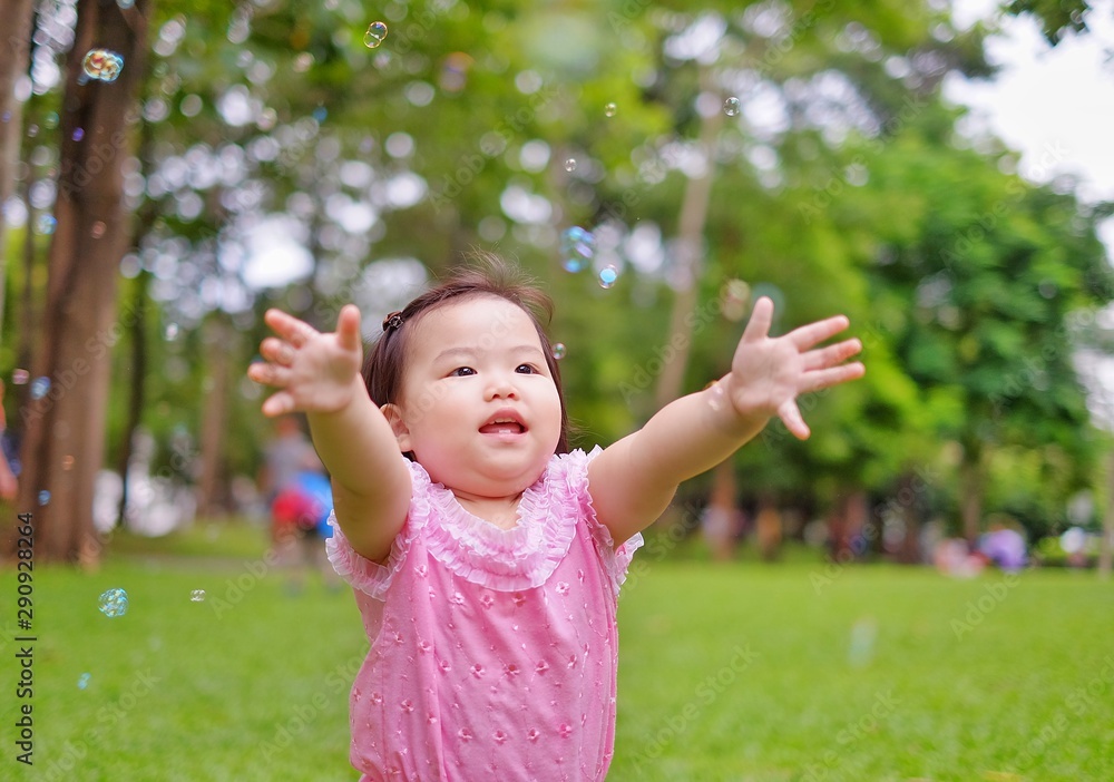 A cute Asian baby playing with bubbles on a grass lawn at a park in Thailand. A cute Asian baby playing with bubbles on a grass lawn at a park in Thailand.