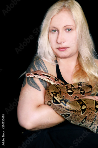 Portrait of girl with Boa constrictor snake. Beautiful woman holds snake in hands and posing in front of camera. Exotic tropical cold blooded reptile, non poisonous Boa constrictor species of snake.