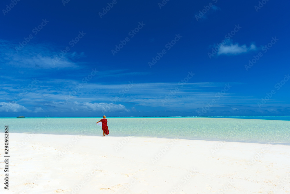 Woman in a red dress on the beach, Aitutaki island, Cook Islands, South Pacific. Copy space for text.