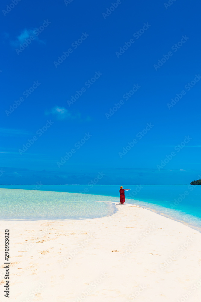 Woman in a red dress on the beach, Aitutaki island, Cook Islands, South Pacific. Copy space for text. Vertical.