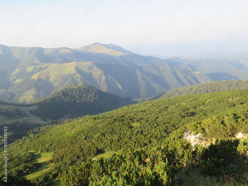 Obraz premium Mountain landscape forested elevations and slopes with distant mountain range