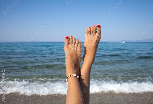 Woman tanned legs on sand beach. Travel concept. Happy feet in a tropical paradise.