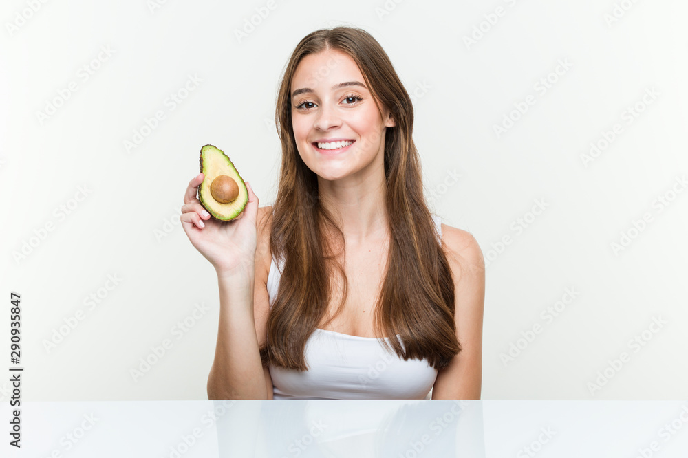 Young caucasian woman holding an avocado happy, smiling and cheerful. Young caucasian woman holding an avocado happy, smiling and cheerful.