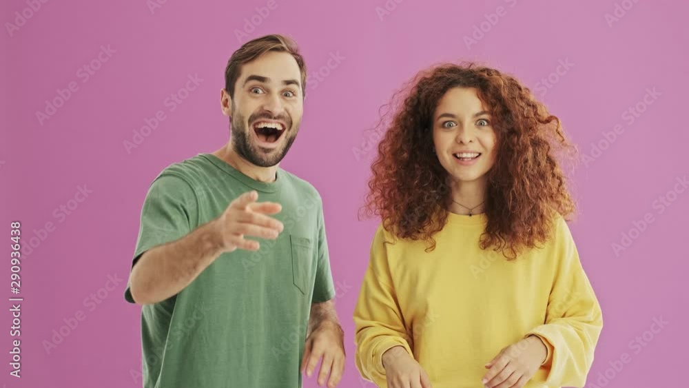 Attractive cheerful young couple making winner gesture and giving high five to each other over pink background isolated Attractive cheerful young couple making winner gesture and giving high five to each other over pink background isolated