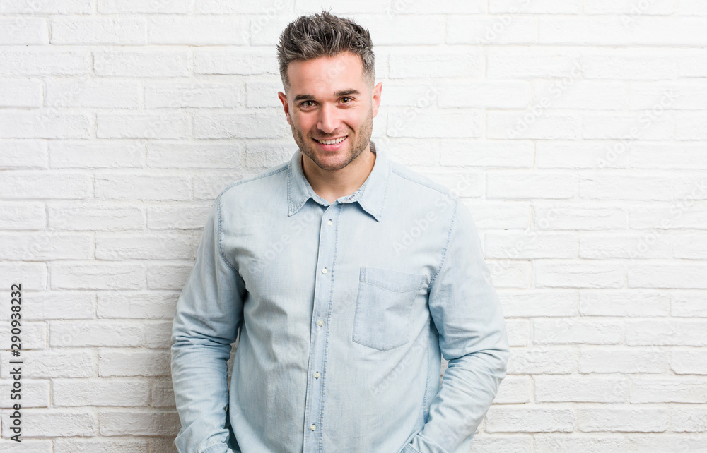 Young handsome man against a bricks wall happy, smiling and cheerful. Young handsome man against a bricks wall happy, smiling and cheerful.