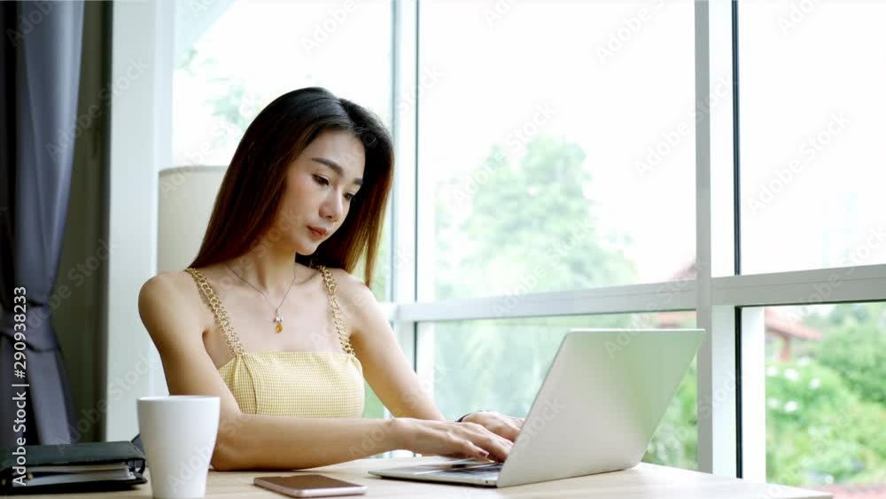 Young beautiful Asian woman enjoying a relaxing moment working and playing with mobile phone in the coffeeshop on a bright sunny day Young beautiful Asian woman enjoying a relaxing moment working and playing with mobile phone in the coffeeshop on a bright sunny day