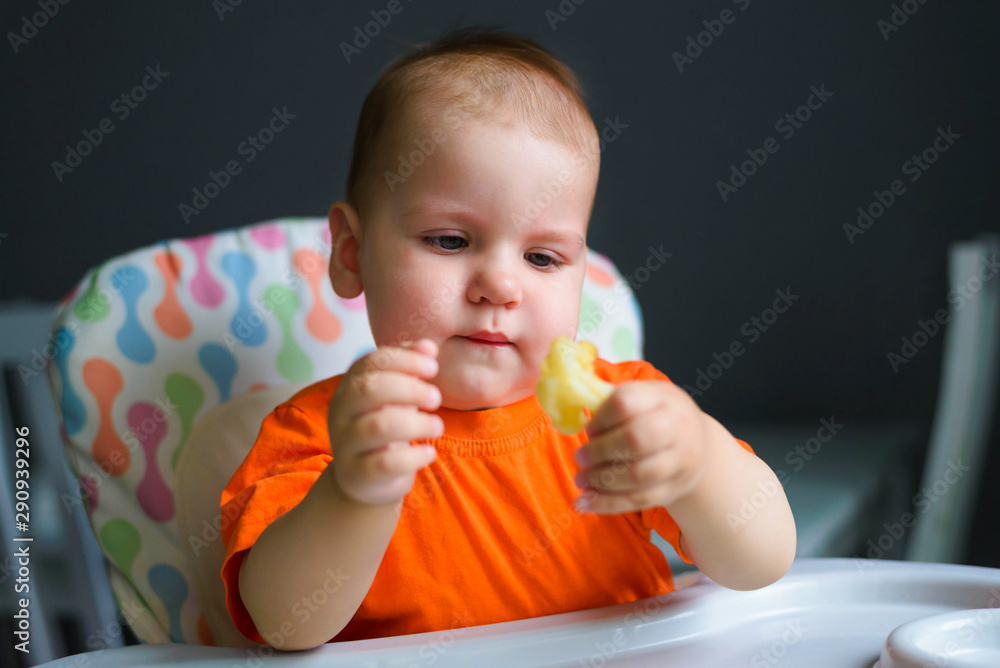 Cute 10 month old boy eats cauliflower and mashed potatoes in his kitchen at home. Baby food, solid food concept. Cute 10 month old boy eats cauliflower and mashed potatoes in his kitchen at home. Baby food, solid food concept.
