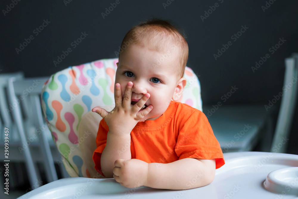 Happy 10 month old boy eats cauliflower and mashed potatoes in his kitchen at home. Baby food, solid food concept. Happy 10 month old boy eats cauliflower and mashed potatoes in his kitchen at home. Baby food, solid food concept.