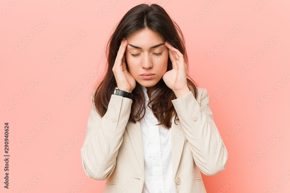 Young brunette business woman against a pink background touching temples and having headache. Young brunette business woman against a pink background touching temples and having headache.