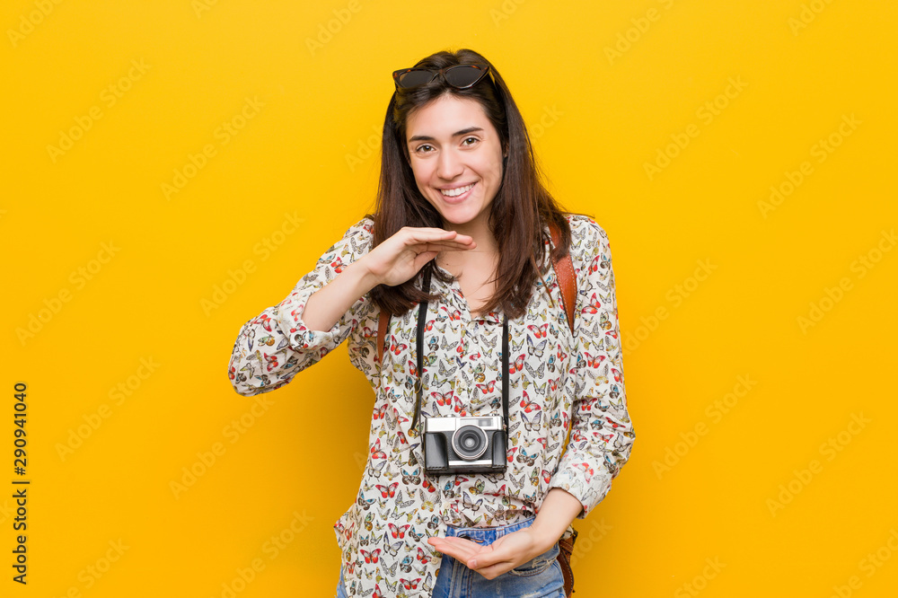 Young brunette traveler woman holding something with both hands, product presentation. Young brunette traveler woman holding something with both hands, product presentation.