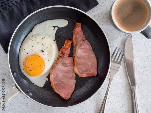 Fotografia Freshly cooked bacon and eggs with a cup of coffee taken from above against a wh