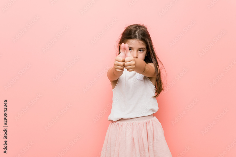 Little girl wearing a princess look with thumbs ups, cheers about something, support and respect concept. Little girl wearing a princess look with thumbs ups, cheers about something, support and respect concept.
