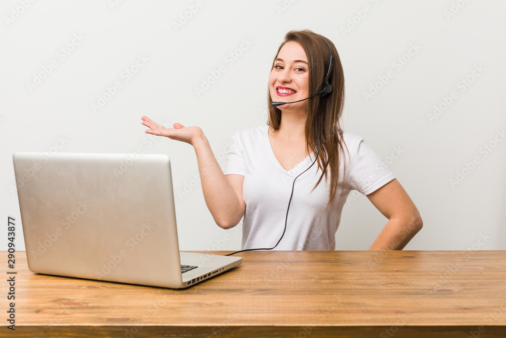 Young telemarketer woman showing a copy space on a palm and holding another hand on waist. Young telemarketer woman showing a copy space on a palm and holding another hand on waist.