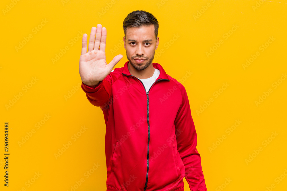 Young filipino fitness man standing with outstretched hand showing stop sign, preventing you. Young filipino fitness man standing with outstretched hand showing stop sign, preventing you.
