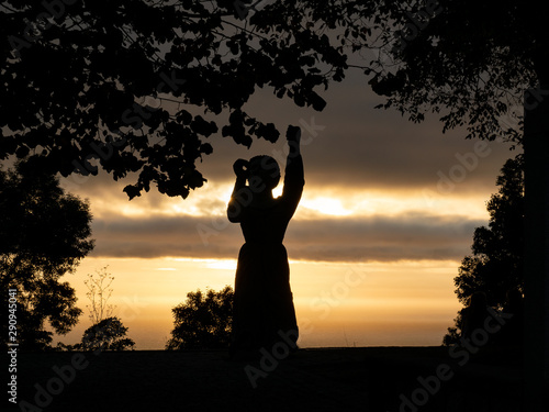 silueta de mujer en actitud de rezo la puesta de sol