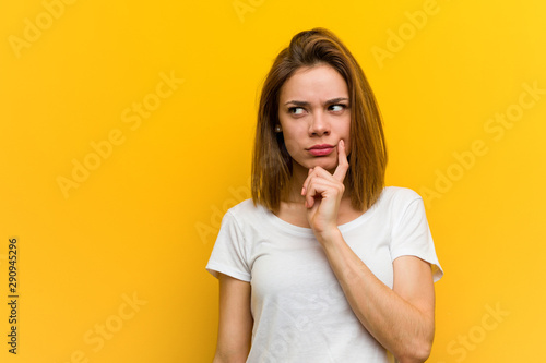 Young natural caucasian woman looking sideways with doubtful and skeptical expression.