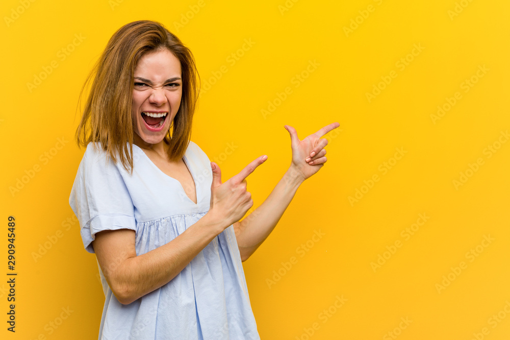 Young pretty young woman pointing with forefingers to a copy space, expressing excitement and desire. Young pretty young woman pointing with forefingers to a copy space, expressing excitement and desire.