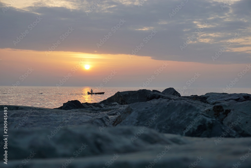 Fisherman in the boat on the sea at sunset.