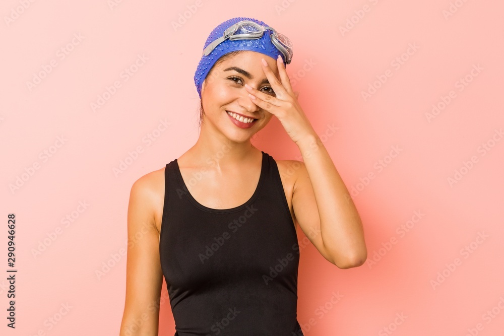 Young arab swimmer woman isolated blink at the camera through fingers, embarrassed covering face. Young arab swimmer woman isolated blink at the camera through fingers, embarrassed covering face.