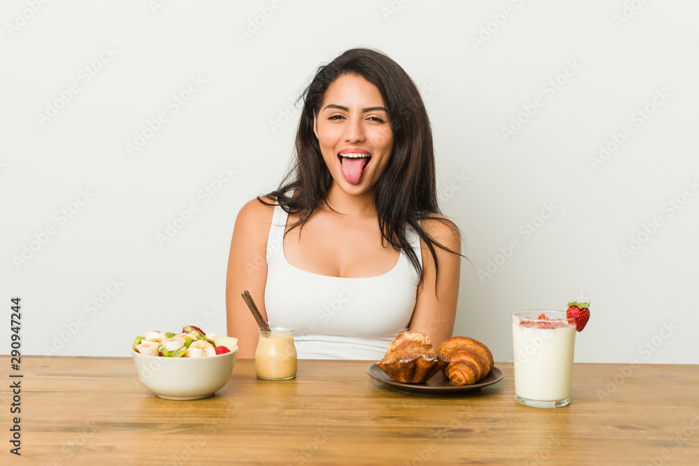 Young curvy woman taking a breakfast funny and friendly sticking out tongue. Young curvy woman taking a breakfast funny and friendly sticking out tongue.