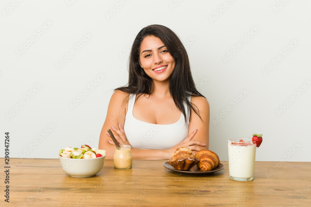 Young curvy woman taking a breakfast who feels confident, crossing arms with determination. Young curvy woman taking a breakfast who feels confident, crossing arms with determination.