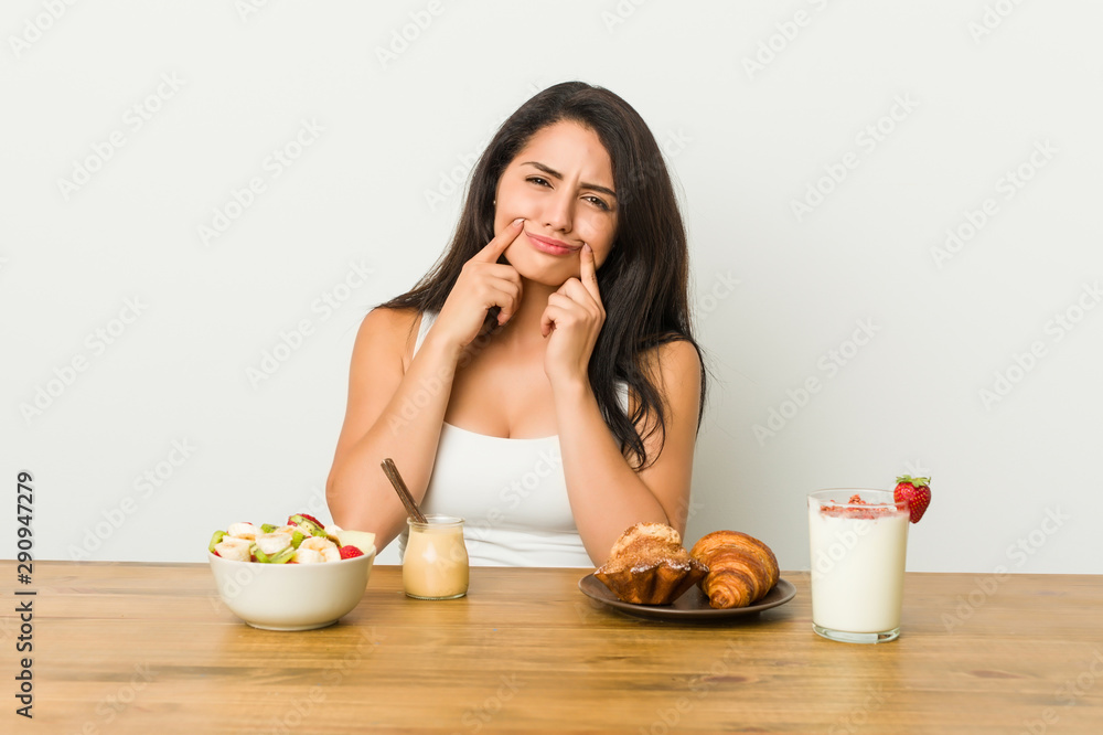 Young curvy woman taking a breakfast doubting between two options. Young curvy woman taking a breakfast doubting between two options.