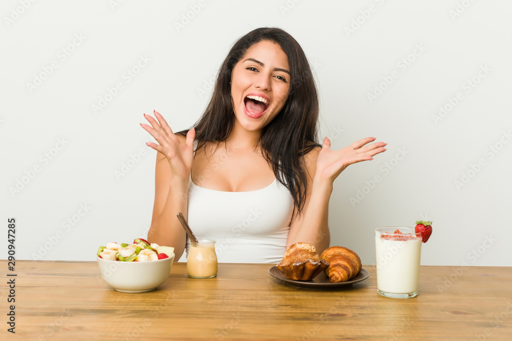 Young curvy woman taking a breakfast celebrating a victory or success, he is surprised and shocked. Young curvy woman taking a breakfast celebrating a victory or success, he is surprised and shocked.