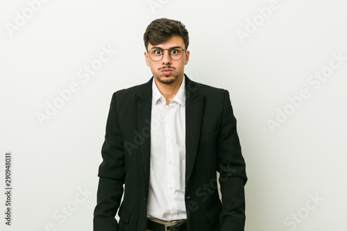 Young business hispanic man blows cheeks, has tired expression. Facial expression concept.
