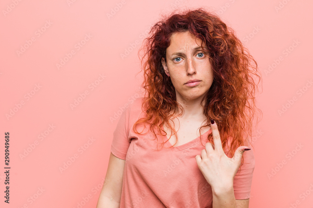 Young natural and authentic redhead woman pointing with finger at you as if inviting come closer. Young natural and authentic redhead woman pointing with finger at you as if inviting come closer.