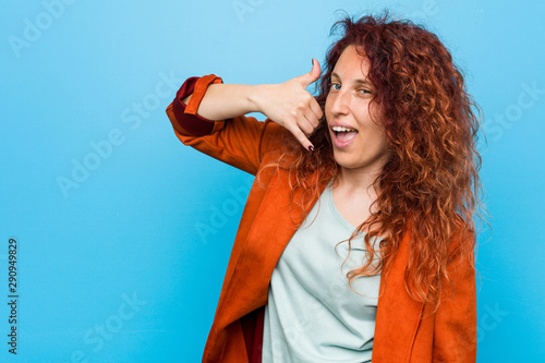 Young redhead elegant woman showing a mobile phone call gesture with fingers.
