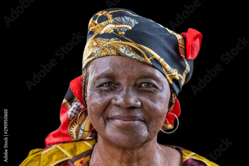 Portrait of African senior citizen woman in her 70- with a happy face in gold and brown dress